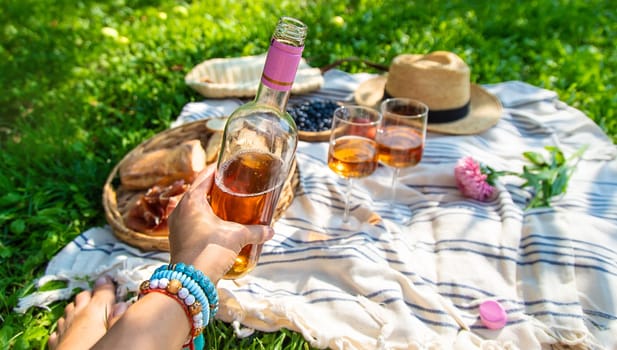 Wine in hands of woman at picnic. Selective focus. Nature.