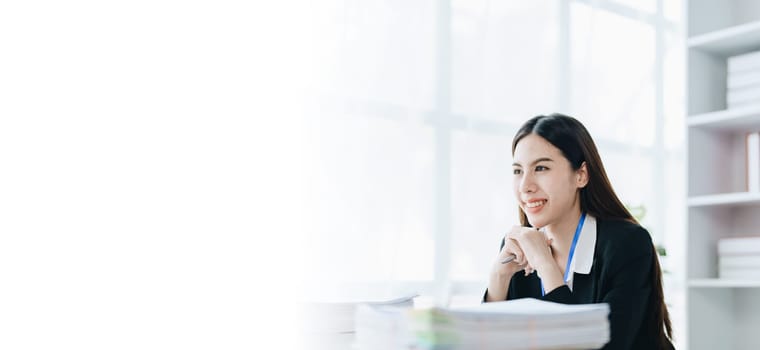 Portrait of a woman business owner showing a happy smiling face as he has successfully invested her business using computers and financial budget documents at work.