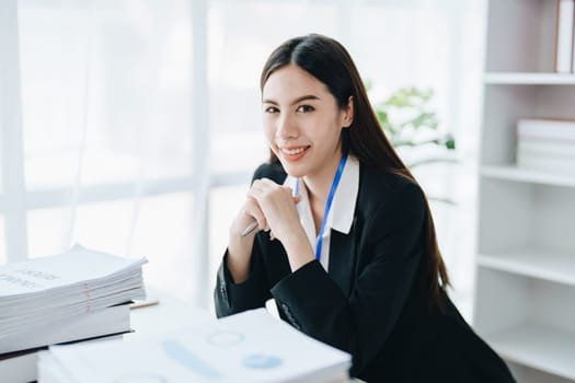 Portrait of a woman business owner showing a happy smiling face as he has successfully invested her business using computers and financial budget documents at work.