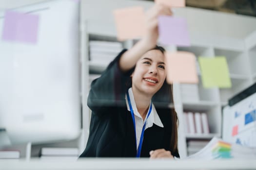 Beautiful young teen asian businesswoman using note pad thinking with planning working on financial document, tax, exchange, accounting and Financial advisor.