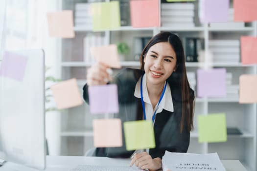 Beautiful young teen asian businesswoman using note pad thinking with planning working on financial document, tax, exchange, accounting and Financial advisor.