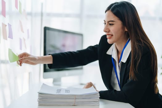 Beautiful young teen asian businesswoman using note pad thinking with planning working on financial document, tax, exchange, accounting and Financial advisor.