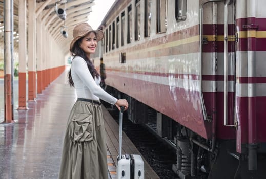 young woman holding a suitcase Happy to travel on holiday by train..