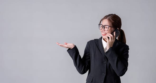 Portrait of a young business woman standing and talking on the phone, pointing, focus according to thoughts..