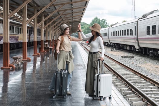 Two young female tourists are happy while waiting for their train at the train station to leave for their holiday..