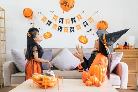 Happy family mother and child happy girl with Halloween at home together beautifully decorated. pretending to release air from a balloon at a child girl.