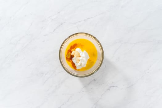 Flat lay. Mixing ingredients in a large glass mixing bowl to bake red velvet bundt cake with cream cheese glaze.