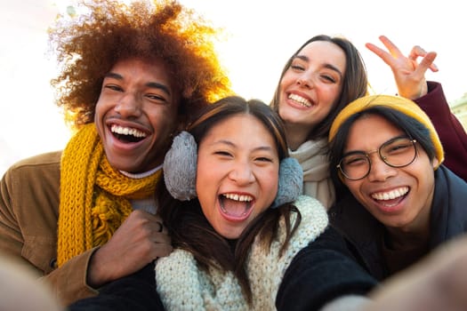 Happy and cheerful multi-ethnic college friends having fun outdoors. Multiracial young group of people taking selfie looking at camera.Gen z, friendship and technology concept.