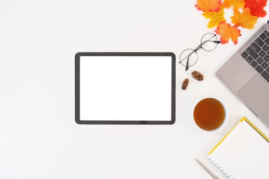 Desk workspace with blank copy space mockup with blank screen tablet, coffee cup, technology, leaves on autumn background. top view freelance business concept for social media.