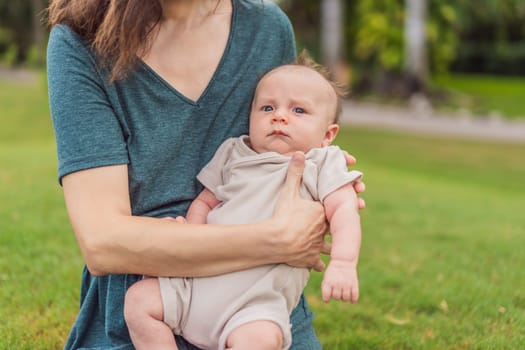 A happy 40-year-old mother cradles her newborn in a sun-drenched park. Love, family and generations in harmony.