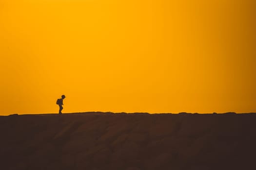A little boy standing on the hill at sunset. Mid shot