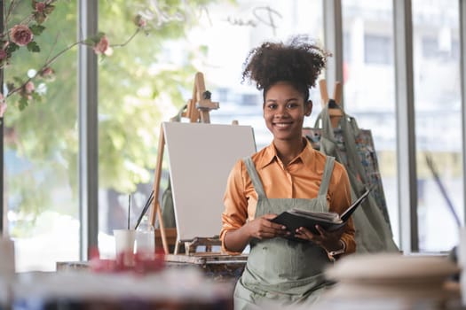 Portrait of a female African artist working on several art projects in her studio with great enjoyment..