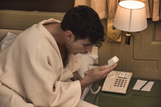 A man in a bathrobe using a phone, screaming into it in frustration or anger