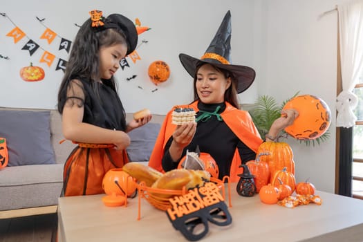 Mother and daughter celebrate on Halloween. Eat cake together at home.