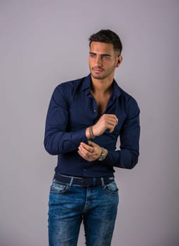 A man in a blue shirt is posing for a picture against grey background in studio shot