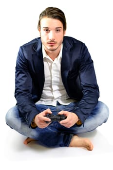 Young adult playing video game, sitting indoors, holding controller or joystick, relaxed posture in studio shot on white background, full body shot