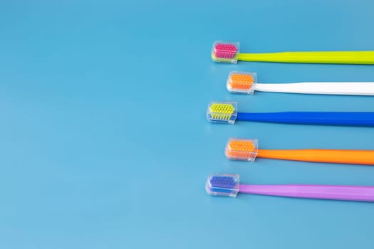 Design Flat Lay Multicolor Toothbrushes on Blue Background, Copy Space. Oral Hygiene, Dental Care, Heathy Tooth And Smile. Sustainable Mouth Product. Horizontal Plane.