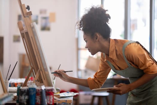 Portrait of a female African artist working on several art projects in her studio with great enjoyment..