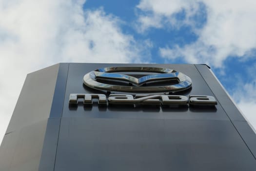 Tyumen, Russia-August 11, 2024: A tall Mazda sign stands prominently against a backdrop of fluffy clouds in a blue sky.