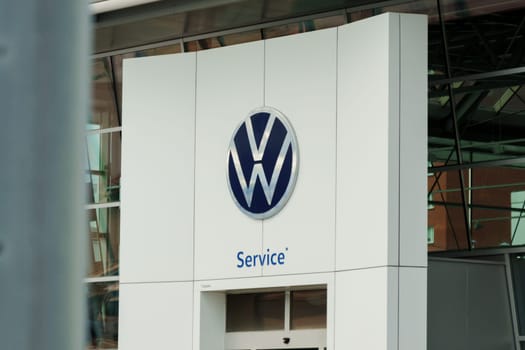 Tyumen, Russia-August 10, 2024: Volkswagen service center exterior with logo and cars parked nearby during daylight