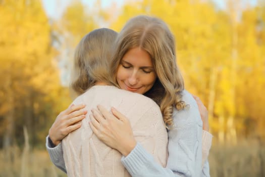 Portrait of happy two women, smiling mature mother and adult daughter hugging in autumn park