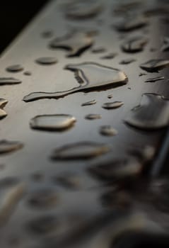 Close up of Rain water drops on the metallic surface. Water droplets caused by rain perched on a stainless steel handle, Natural Pattern of raindrops or dew drops on silver metal background for wallpaper poster and banner design, Selective focus.