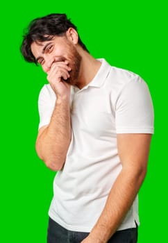 Young man with a beard smiles and poses in front of a bright green background close up