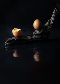 View of Broken raw chicken egg and Fresh chicken egg (Hen eggs) on Log with Dark background. Fresh eggs from the farmer, Natural organic healthy food concept, Space for text, Selective focus.