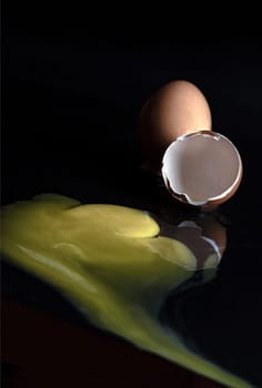 View of Broken egg yolk with Broken raw chicken eggshell in front of Fresh chicken egg (Hen eggs) on Dark background. Fresh eggs from the farmer, Natural organic healthy food concept, Space for text, Selective focus.