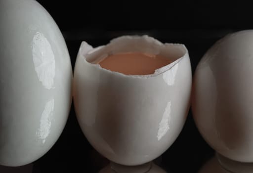 Three raw duck eggs are sitting in a row with an egg in the middle broken in half showing the yolk and white egg on dark background. use it as your Wallpaper, Poster and Space for text, Selective focus.
