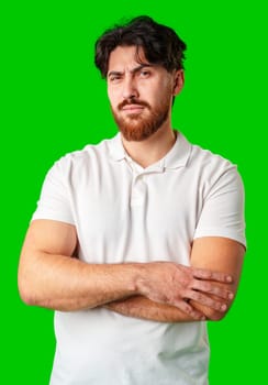 A man with a serious expression stands with crossed arms against a vibrant green background close up