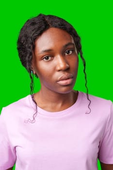 Young woman with an expression of contemplation poses against a bright green background in studio