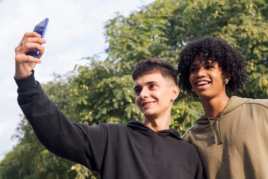 multiethnic group of two male teens smiling happy taking selfie photo with mobile phone, concept of youth lifestyle and technology of communication