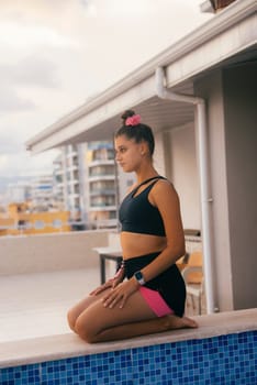 A serene scene of a young woman in yoga pose at a rooftop pool, embracing tranquility and mindfulness.