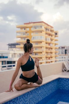 A peaceful and serene moment of yoga practice is taking place beside a stunning pool in an urban atmosphere