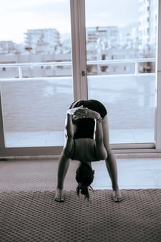 A woman practices yoga in a serene, modern space, showcasing her flexibility and inspiring focused intent