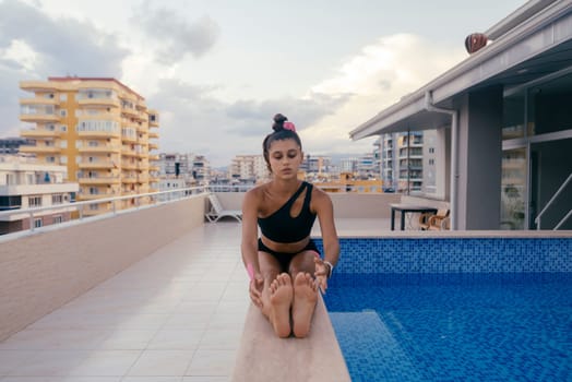 A woman stretches by a beautiful pool, embodying relaxation and mindfulness in a contemporary setting