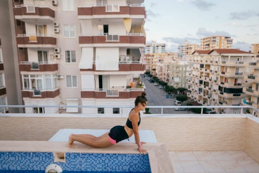 A peaceful and serene yoga session takes place on a rooftop pool that overlooks a stunning urban scenery