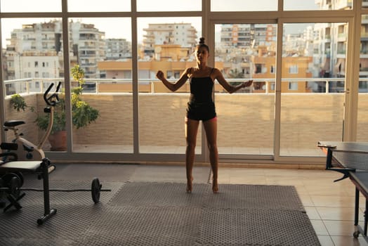 A woman performs a dynamic home workout, enjoying a beautiful urban view and embracing a healthy lifestyle