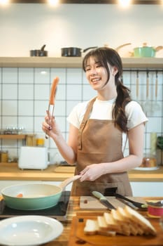 Young beautiful woman in apron preparing breakfast at the kitchen.