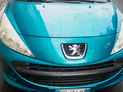 Cremona, Italy September 26th 2024 Close up of a blue peugeot 207 front, with water drops on the hood after the rain