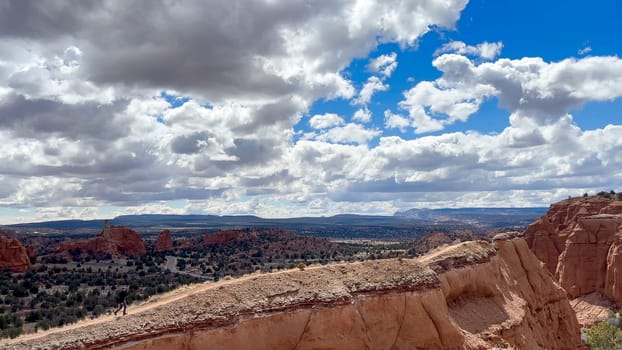 A male hiker walking on a trail towards a steep ridge at Kodachrome Basin State Park, Utah. With a scenic view of the valley floor and surrounding stunning landscape - USA