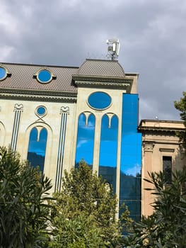 Tbilisi Georgia city ​​center, administration building with beautiful windows, green trees street, blue sky landscape architecture, clouds. High quality photo