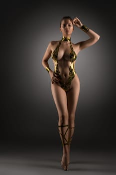 Well-shaped nude woman with gold tape body adornment full-length shot