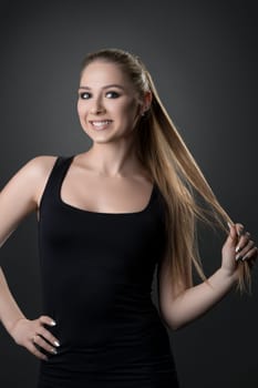 Happy fitness model wearing black top and leggings cropped shot against gray wall