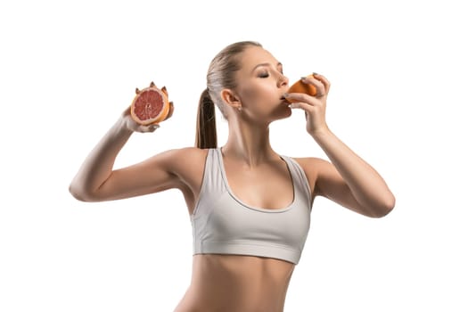 Beautiful fitness trainer biting a grapefriut cropped isolated view on white background