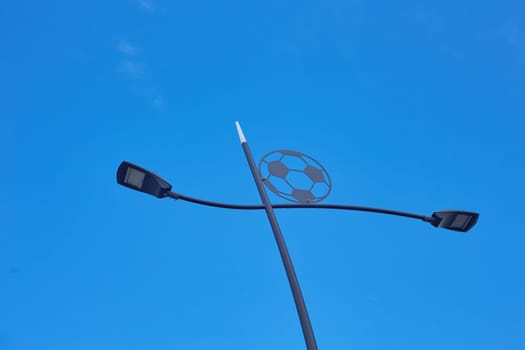 NIZHNY NOVGOROD, RUSSIA - JULY 31, 2024: Black metal street lighting poles with a soccer ball on the road next to the stadium.