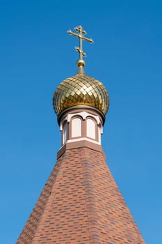 The church's beautiful golden dome shines brightly under the clear blue sky. Intricate patterns adorn the dome, showcasing impressive architectural design and craftsmanship.