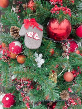 A lively Christmas tree showcases vibrant red ornaments, decorative mittens, and pine cones, creating a joyful atmosphere perfect for the holiday season and festivities.