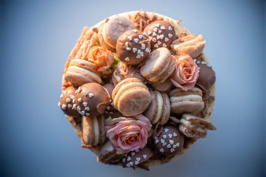 Delicious birthday cake decorated with macarons and chocolate balls is waiting for the guests to come and celebrate